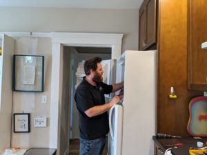 A technician inspecting a refrigerator inside a kitchen.